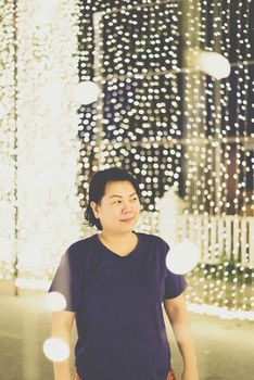 Asian woman 40s plump body fashion happy for relax in night time with bokeh of light decoration for happy new year celebration