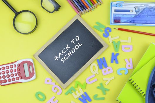 Student backpack and various school supplies. Studying, education and back to school concept. Yellow background and selective focus.