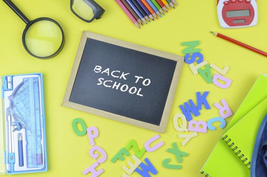 Student backpack and various school supplies. Studying, education and back to school concept. Yellow background and selective focus.