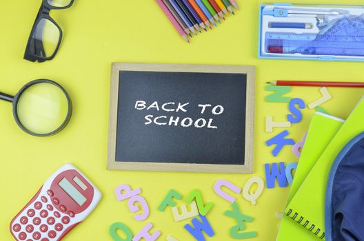 Student backpack and various school supplies. Studying, education and back to school concept. Yellow background and selective focus.