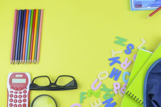 Student backpack and various school supplies. Studying, education and back to school concept. Yellow background and selective focus.