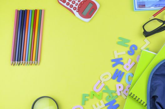 Student backpack and various school supplies. Studying, education and back to school concept. Yellow background and selective focus.