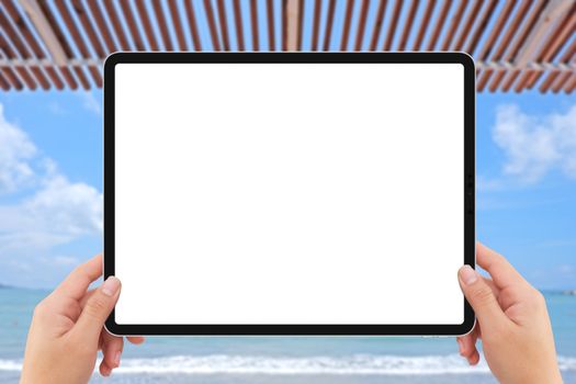 The human two hands holding white tablet computer white screen mockup near beach