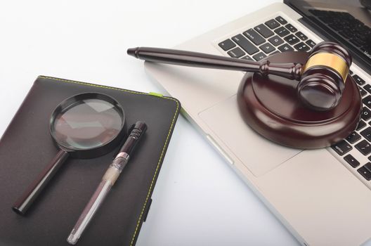 Cyber crime concept. Judge hammer or gavel with laptop on white background. Selective focus.