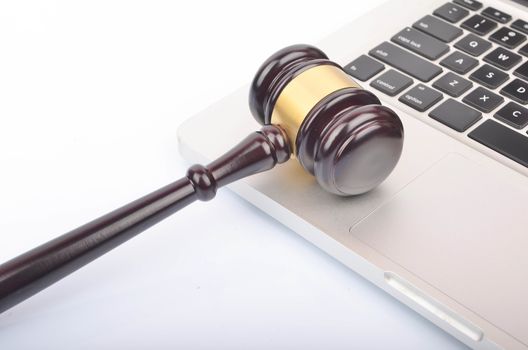 Cyber crime concept. Judge hammer or gavel with laptop on white background. Selective focus.