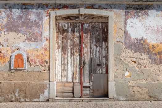 very old worn wooden door with peeling paint in portugal