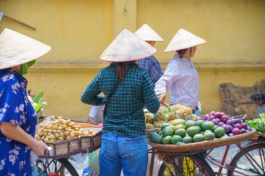 Back view of Women, Female street vendor in fruit, flowers market on the bike and street in VIETNAM HANOI