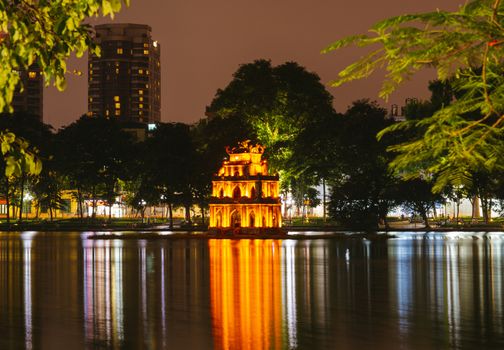 OLD QUARTER, HANOI/VIETNAM - JULY 16: Night view of The Huc bridge and Ngoc Son temple on 07 16 2019 in Lake of the Returned Sword, Hoan Kiem Lake, Turtle Tower. City view of background.