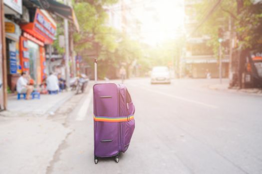 Purple Luggage strap or suitcase on the streets rood of big cities when traveling backpacker on vacation day  in HANOI VIETNAM sunlight, flare,  beautiful trees and blur background concept.