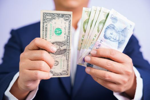 Money in China and USA hold on hand business man wearing a blue suit CNY, USD Pay, exchange money People’s Republic of China (PRC), america on white background.