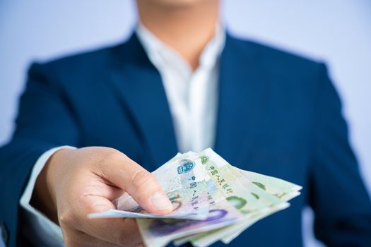 Money in China hold on hand business man wearing a blue suit CNY, Pay, exchange money People’s Republic of China (PRC) on white background.