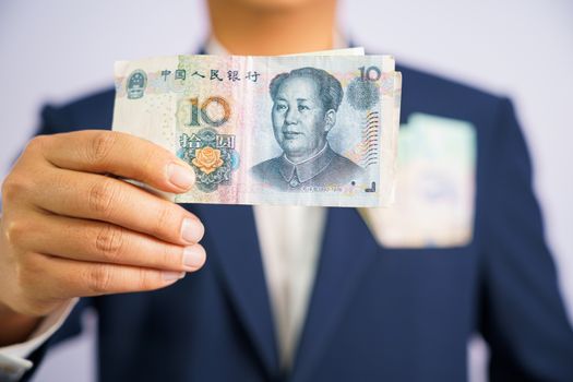 Money in China hold on hand business man wearing a blue suit CNY, Pay, exchange money People’s Republic of China (PRC) on white background.