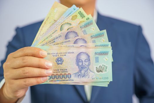 Money in Vietnam hold on hand business man wearing a blue suit (Socialist Republic Of Vietnam), Dong, VND, Pay, exchange money vietnamese on white background.