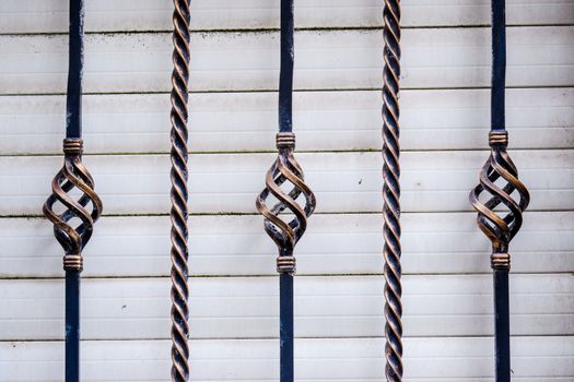 Twisted iron railing with a white shutter in background UK