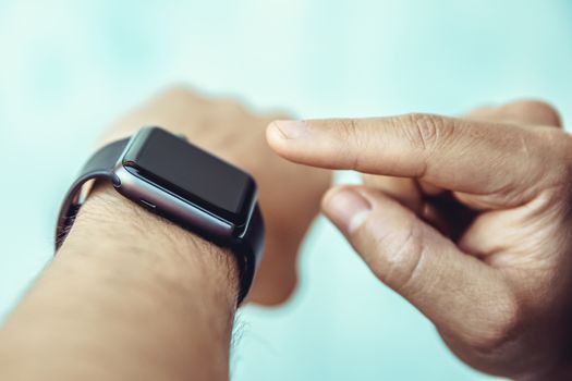 The man controls by touching his finger a smart watch on his hand.