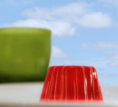 Close-up of a strawberry jelly dessert with a green glass and a cloudy sky in the background