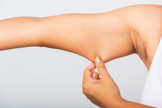 Close up of Asian woman pulling excess fat on her under arm, problem armpit skin, studio isolated on white background, Healthy overweight excess body concept