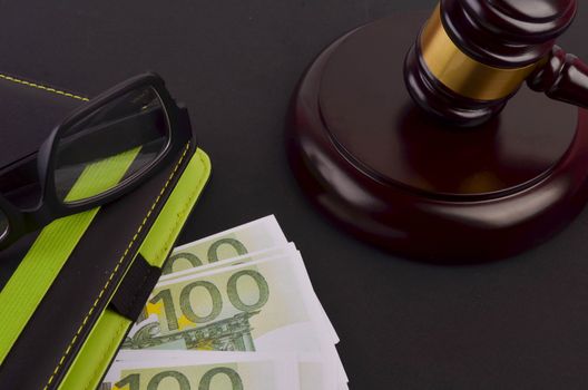 Gavel for judge lawyer with Euro banknotes on black background.