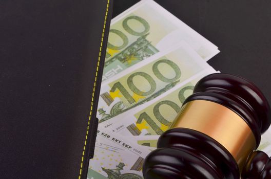 Gavel for judge lawyer with Euro banknotes on black background.