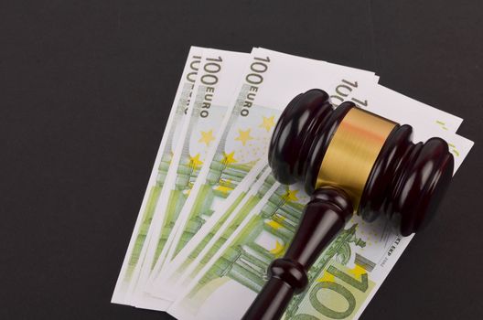 Gavel for judge lawyer with Euro banknotes on black background.