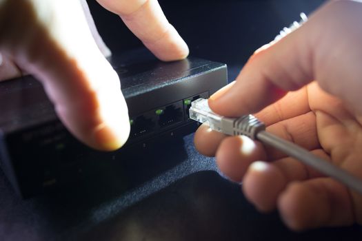 Close-up Hand holding ethernet cable on network switches background