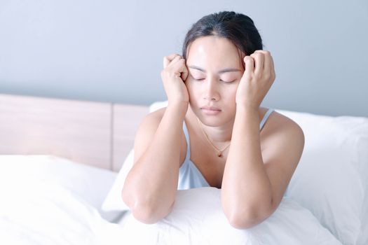 Closeup woman sitting on bed in the bedroom with thinking or depressed feeling, selective focus