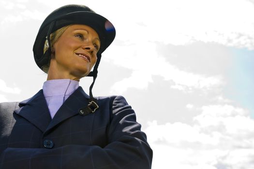A blonde equestrian model poses outdoors before a horse show