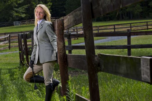 A blonde equestrian model poses outdoors before a horse show