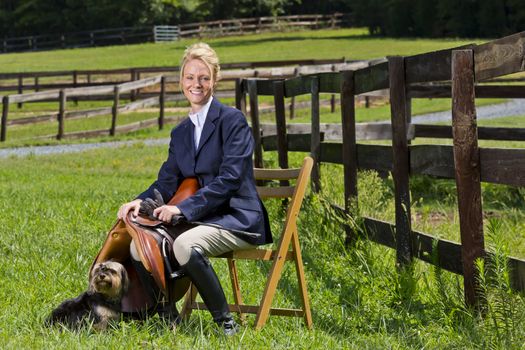 A blonde equestrian model poses outdoors before a horse show