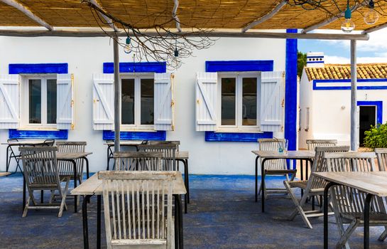 Restaurant tables with chairs on terrace near Praia da Rocha beach on coast of Portimao, Algarve, Portugal. Tables on terrace in small coastal restaurant with sea view near Portimao town, Portugal.
