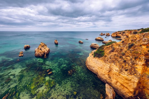 View of stunning beach with golden color rocks in Alvor town , Algarve, Portugal. View of cliff rocks on Alvor beach, Algarve region, Portugal.