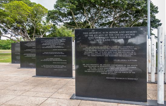 Oahu, Hawaii, USA. - January 10, 2020: Pearl Harbor, Line of black steles, marble slabs with texts at USS Oklahoma memorial. Green foliage in back.
