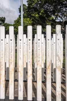 Oahu, Hawaii, USA. - January 10, 2020: Pearl Harbor, Closeup of group of white name-sticks at USS Oklahoma memorial. Green foliage in back.