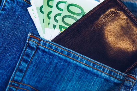 Brown wallet with euro money in the blue jeans pocket. Wallet with Euro banknotes. Cash in the wallet in the blue jeans pocket. Euro money in leather wallet.