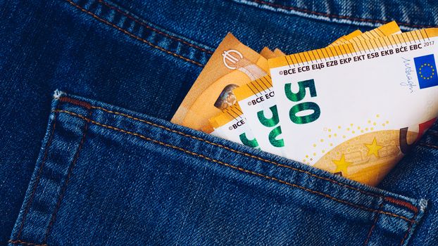 Euro bills in jeans pocket background. Euro banknotes in jeans back pocket. Concept of rich people, saving or spending money. Euro bills falling out. Easy to steal the money. Irresponsible action.