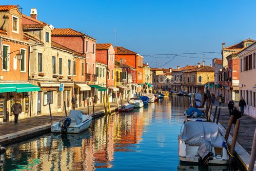 Murano glass making island, water canal, bridge, boat and traditional buildings. Venice or Venezia, Italy, Europe.