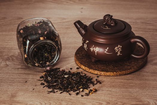 Asian teapot on stand and jar with scattering of fruit tea, inscription on the teapot: stone art treasures of God