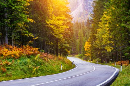 Mountain road. Landscape with rocks, sunny sky with clouds and beautiful asphalt road in the evening in summer. Vintage toning. Travel background. Highway in mountains.  