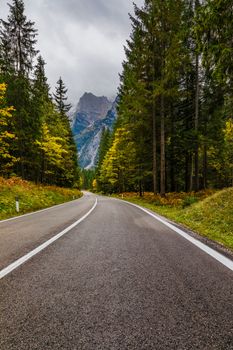 Mountain road. Landscape with rocks, sunny sky with clouds and beautiful asphalt road in the evening in summer. Vintage toning. Travel background. Highway in mountains.  