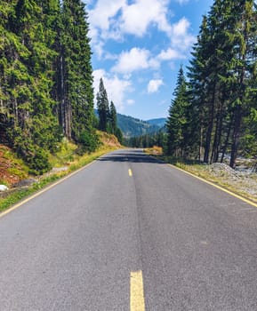 Mountain road. Landscape with rocks, sunny sky with clouds and beautiful asphalt road in the evening in summer. Vintage toning. Travel background. Highway in mountains. Transportation