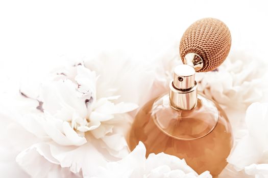 Fragrance bottle as vintage perfume product on background of peony flowers, parfum ad and beauty branding design