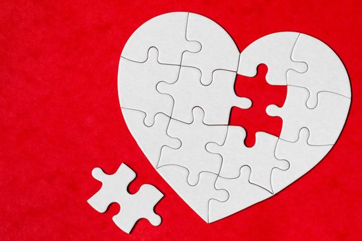 Heart-shaped jigsaw puzzle on color background. Puzzle heart on wooden background. A missing piece of the heart puzzle. Heart shape jigsaw puzzle. Puzzles in the shape of a heart. 