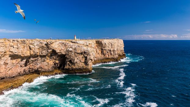 Lighthouse in Fortaleza de Sagres, Portugal, Europe on a cliff. This beautiful ancient architecture is used for navigation by ships and boats. Great destination for tourists on vacation. Portugal.
