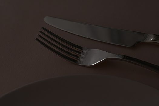 Empty plate and cutlery as mockup set on dark brown background, top tableware for chef table decor and menu branding design