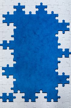 Framing in the form of a rectangle, made of a white jigsaw puzzle. Frame text and jigsaw puzzles. Frame made of jigsaw puzzle pieces on blue background.