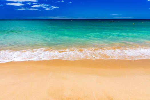 Soft wave of blue ocean on sandy tropical beach. Background of tropical paradise beach with golden sand, travel tourism panorama background concept. Sand and sea waves background.