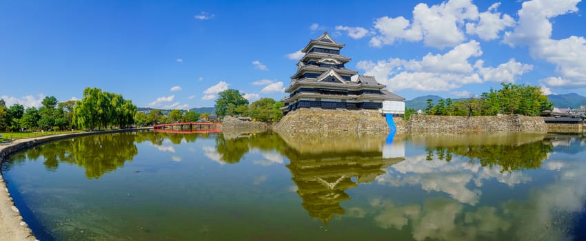 Matsumoto, Japan - October 1, 2019: Panoramic view of the Matsumoto Castle (or Crow Castle) and bridge, with locals and visitors, in Matsumoto, Japan