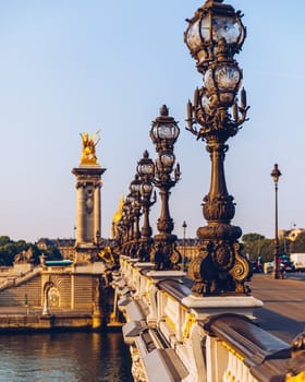 Pont Alexandre III bridge over river Seine in the sunny summer morning. Bridge decorated with ornate Art Nouveau lamps and sculptures. The Alexander III Bridge across Seine river in Paris, France.