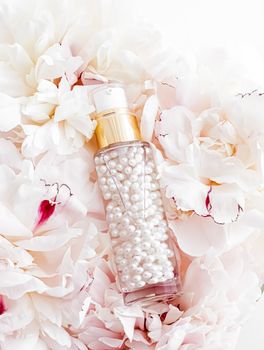 Luxurious cosmetic bottle as antiaging skincare product on background of flowers, blank label packaging for body care branding design