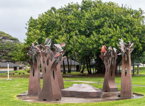 Kahului, Maui,, Hawaii, USA. - January 12, 2020: Closeup of Brown rusty metal group of trees statue on green lawn at University of Hawaii, Maui college campus. Gray cloudy sky. Green foliage in back.